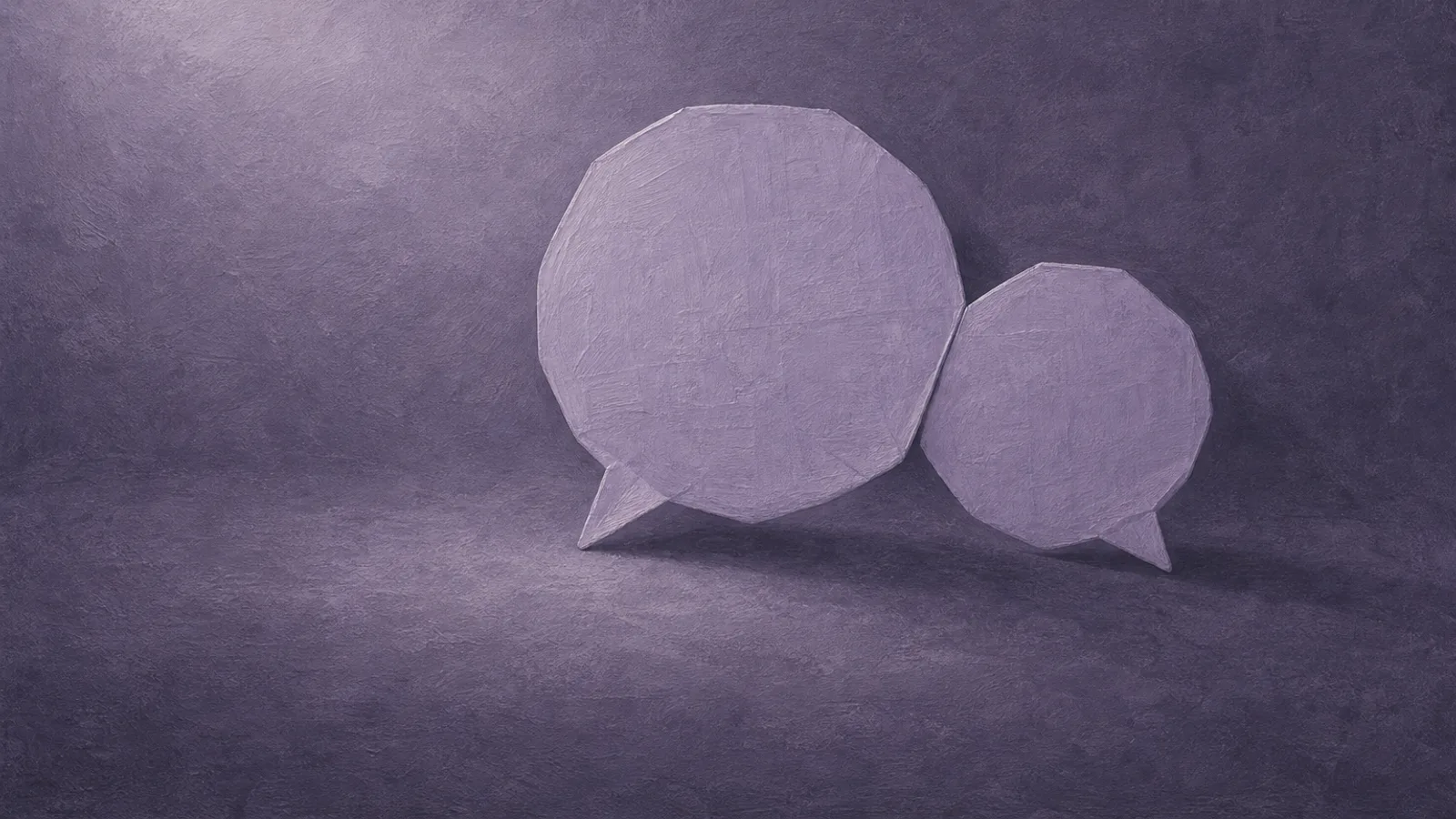 Two paper speech bubbles of different sizes leaning gently together, on a dusty-violet surface