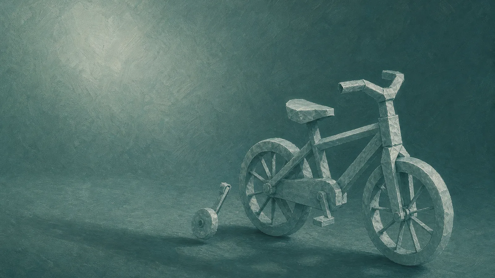 A small paper bicycle with one training wheel taken off and standing beside it