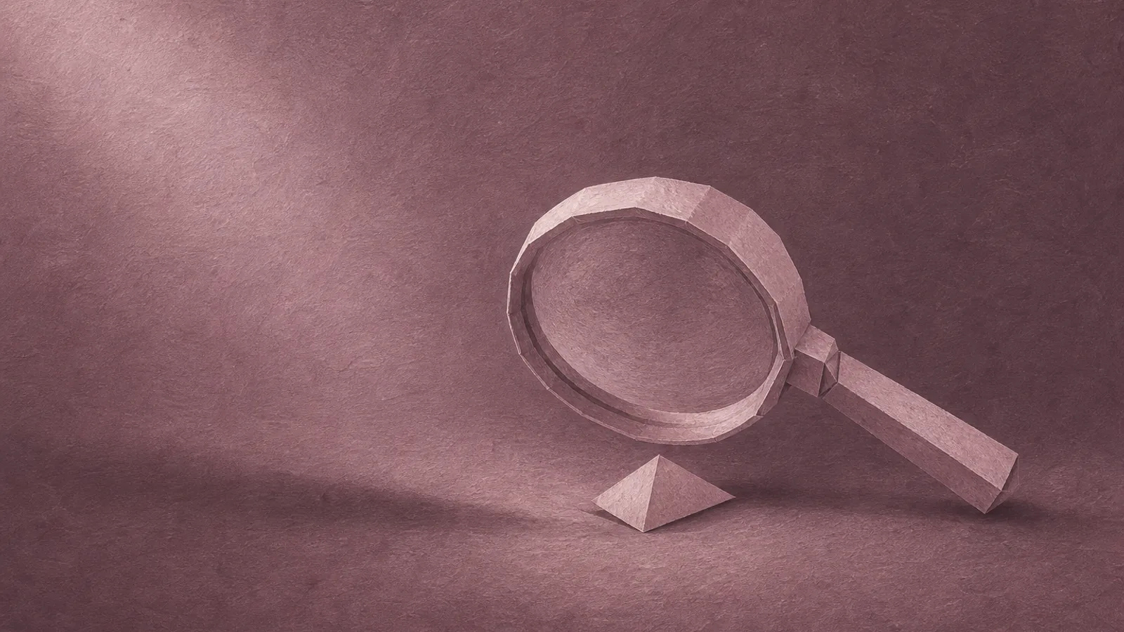 A folded paper magnifying glass resting over a small paper shape on a plain surface
