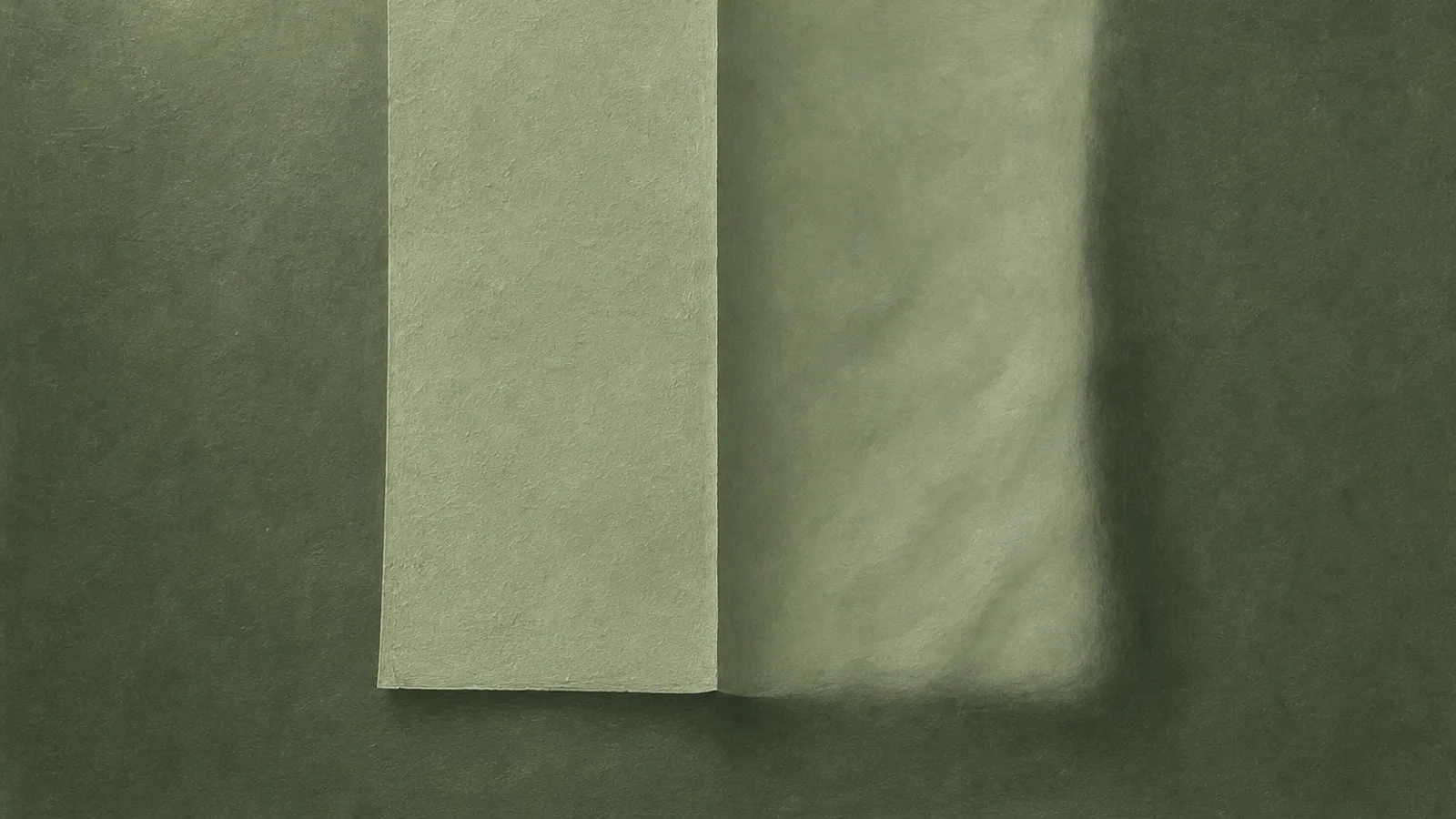 A sheet of paper folded into two halves on a sage surface, one crisp and one softly blurred